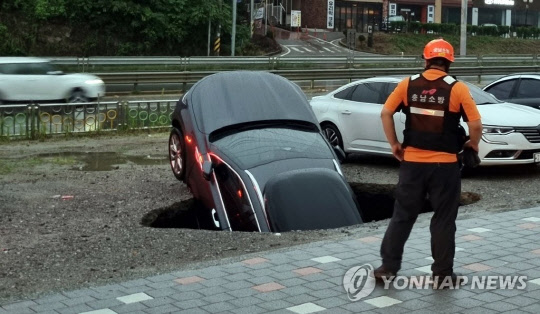 지난 1일 오전 충남 당진시 서해로 한 공터에 대형 싱크홀이 발생해 차량 1대 차체 절반이 이상이 빠져 있다. 연합뉴스